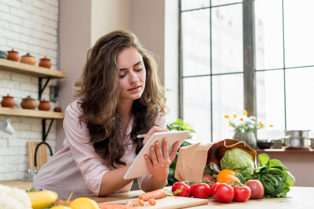 brunette-woman-kitchen-making-healthy-low-calories-salad-while-watching-movie-online-laptop-computer-RumboMag - Weight loss is a shared goal for some people, and for good reason-Rumbomag