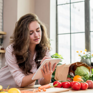 brunette-woman-kitchen-making-healthy-low-calories-salad-while-watching-movie-online-laptop-computer-RumboMag - Weight loss is a shared goal for some people, and for good reason-Rumbomag