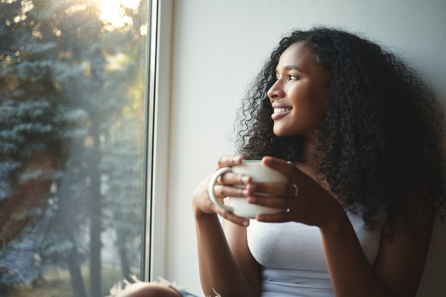 morning-routine-portrait-happy-charming-young-mixed-race-female-with-wavy-hair-enjoying-summer-view-through-window-drinking-good-coffee-sitting-windowsill-smiling-beautiful-daydreamer - Positive thinking is looking at things from a positive perspective - RumboMag