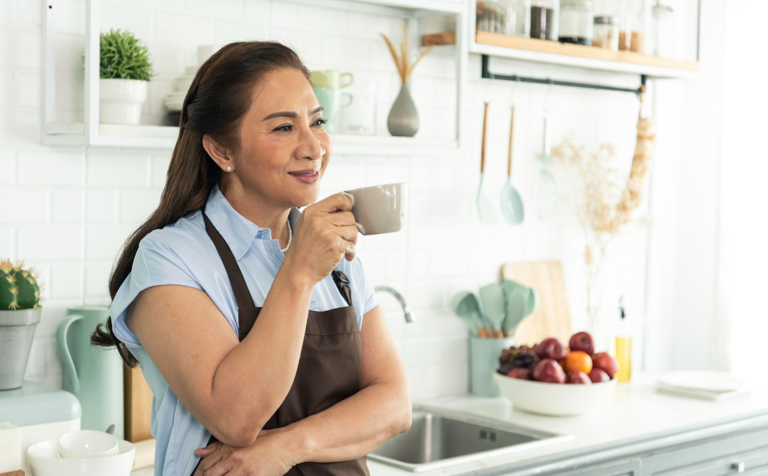 relax-asian-older-woman-apron-holding-cup-coffee-kitchen-room - If you’re a woman over 50, it’s often difficult to know which diet is best, especially as you’re experiencing physical changes associated with aging - Rumbomag